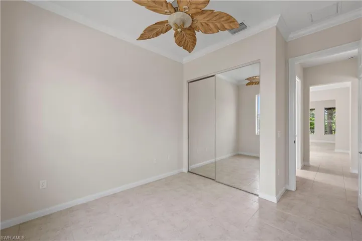Unfurnished bedroom with ornamental molding, a closet, baseboards, light tile patterned flooring, and ceiling fan