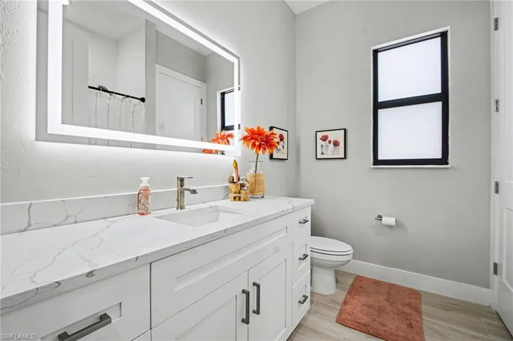 Guest Bathroom with a shower with curtain, vanity, light wood-type flooring, and plenty of natural light