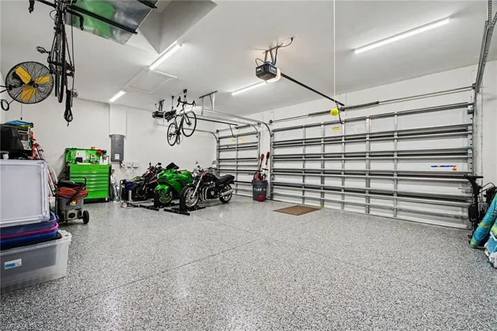 Garage featuring electric panel, epoxy floors and a garage door opener