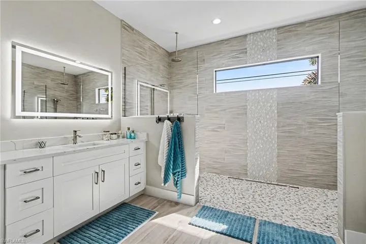Master bath featuring walk in shower, vanity, and light wood finished floors