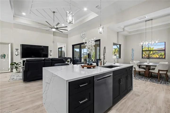 Kitchen with dark cabinetry, pendant lighting, a chandelier, ornamental molding, and a high ceiling