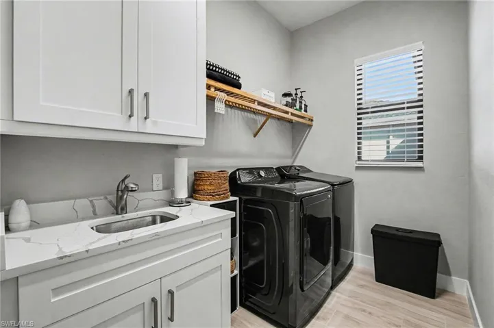Washroom with cabinet space, separate washer and dryer, and light wood-type flooring