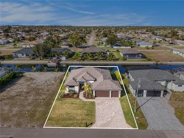 Aerial view of residential area with property boundaries highlighted and a large body of water