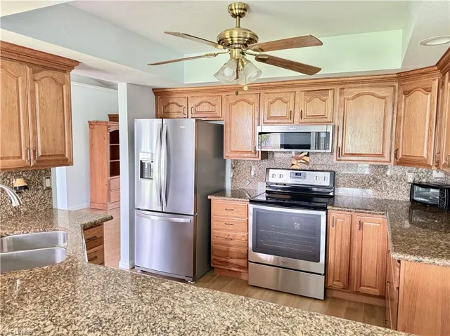 Kitchen with a bar to sit and eat at and appliances with stainless steel finishes