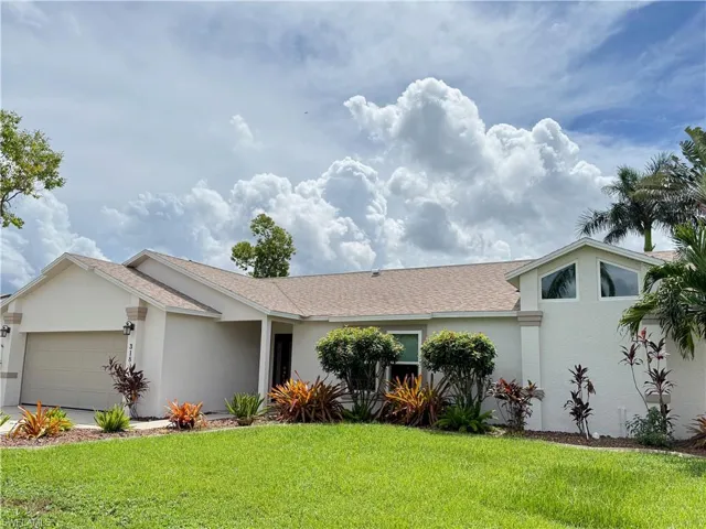 View of front of house featuring 2018 roof with shingles, stucco siding, Newer impact windows, a front lawn, and a garage