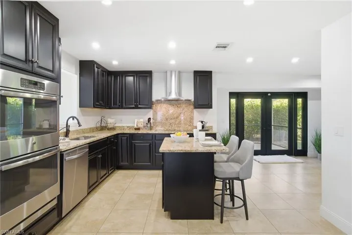 Spacious kitchen with island, electric cooktop and stainless exhaust hood provide the perfect setting and tools for entertaining or managing your family