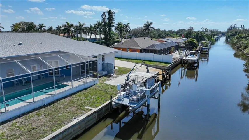 View of dock featuring a water view, a fenced in pool, and glass enclosure