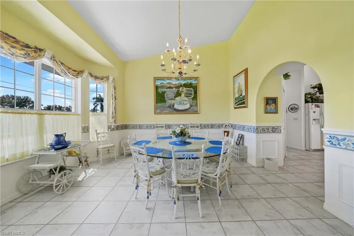 Dining area featuring vaulted ceiling, light tile patterned floors, and a chandelier