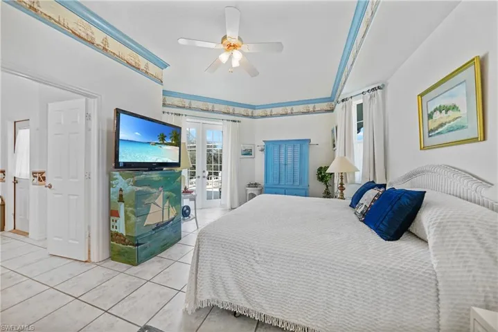 Bedroom featuring light tile patterned floors, access to exterior, ceiling fan, and french doors