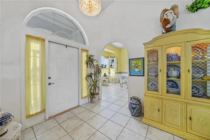 Tiled entryway with a notable chandelier