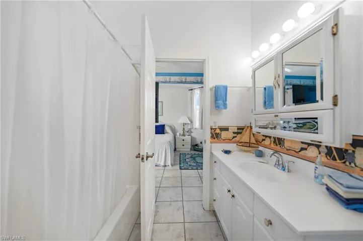 Bathroom featuring vanity, tile patterned floors, and shower / bathtub combination with curtain