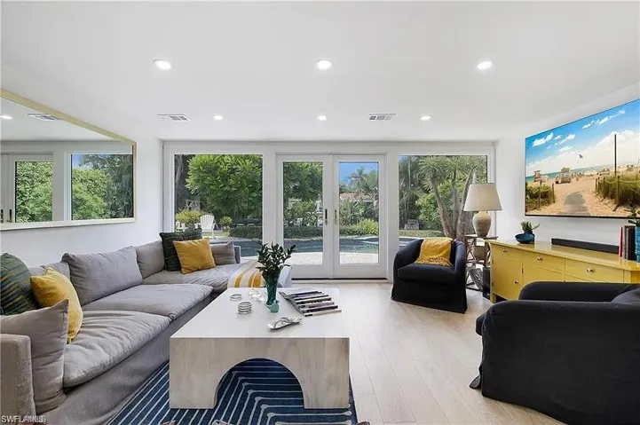 Living room with french doors, light wood finished floors, healthy amount of natural light, and recessed lighting