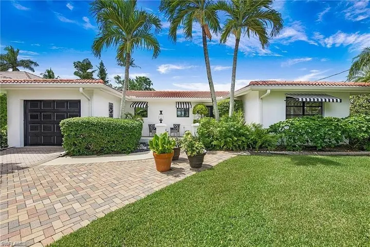 Mediterranean / spanish-style house featuring a garage, stucco siding, a front yard, and decorative driveway