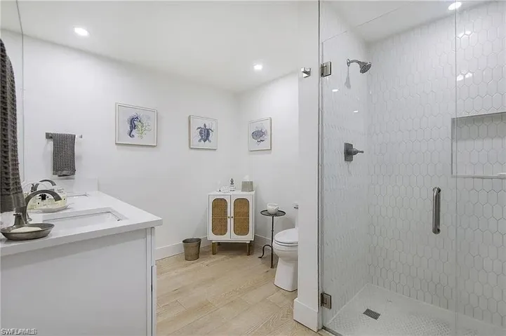 Bathroom featuring double vanity, light wood finished floors, a stall shower, and recessed lighting