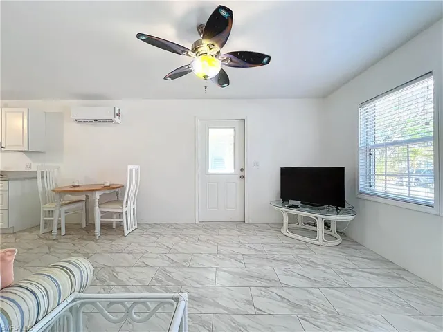 Living room with a wall unit AC and ceiling fan