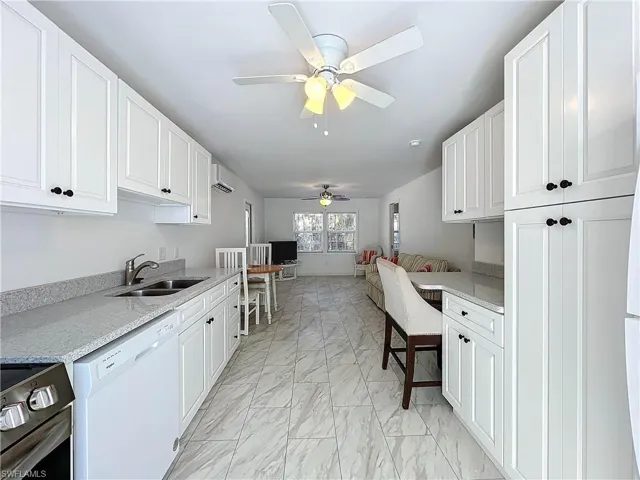 Kitchen featuring sink, dishwasher, a wall unit AC, white cabinets, and electric stove