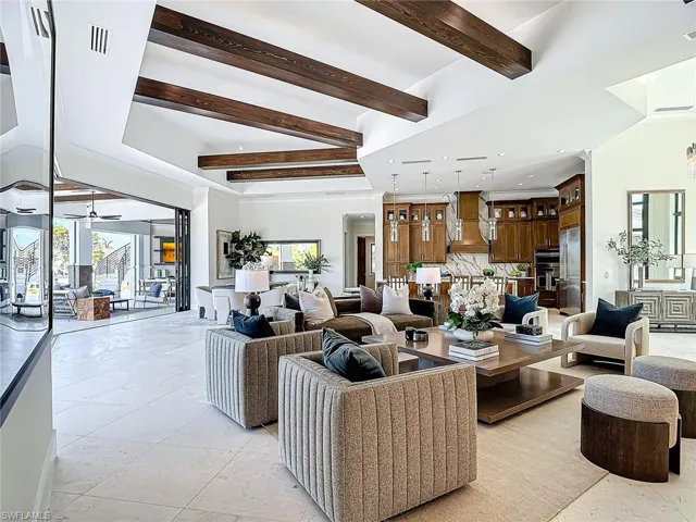 Volume ceilings with gleaming exposed wood beams.  Shell stone continues into the covered lanai.