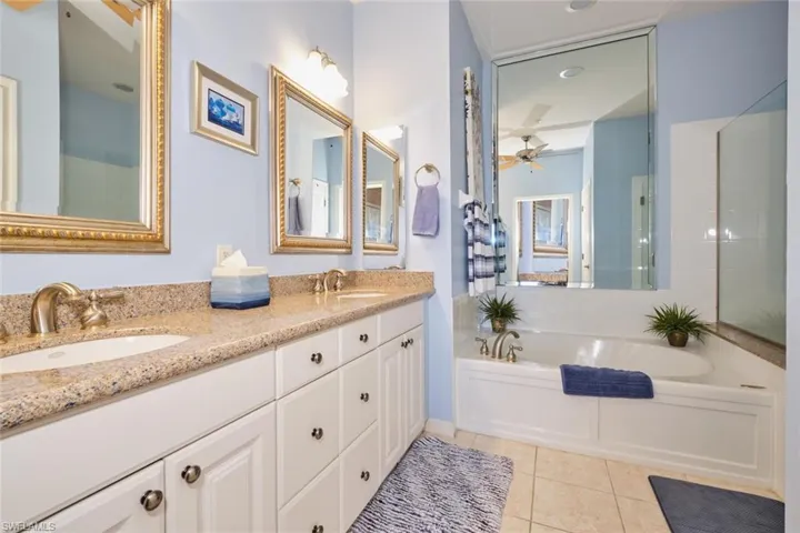 Bathroom featuring tile vanity, ceiling fan, and a bathing tub