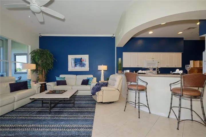 Tiled living room featuring ceiling fan and crown molding