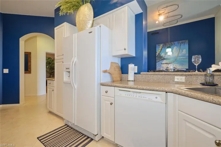 Kitchen with white cabinets, white appliances, ornamental molding, and light tile patterned floors