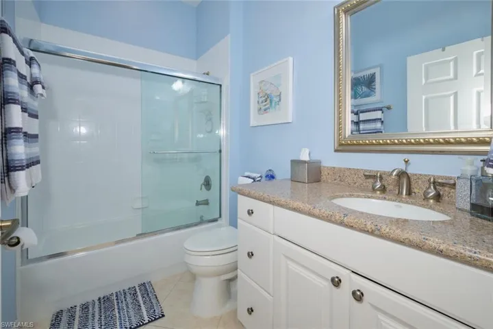 Full bathroom featuring tile patterned flooring, vanity, toilet, and bath / shower combo with glass door