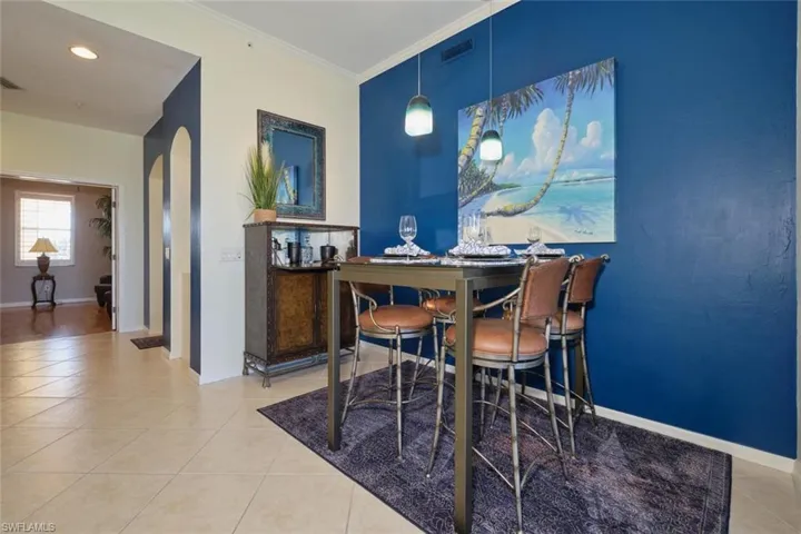 Dining area with light tile patterned flooring and crown molding
