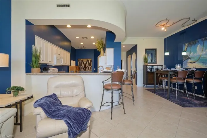 Kitchen featuring a kitchen breakfast bar, kitchen peninsula, light tile patterned flooring, and ornamental molding