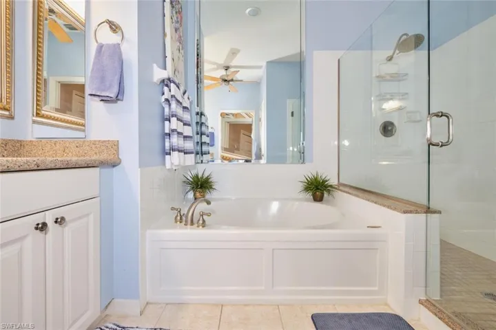 Bathroom featuring tile patterned flooring, vanity, separate shower and tub, and ceiling fan