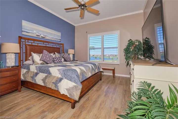 Bedroom featuring ceiling fan, ornamental molding, and light  wood-style flooring