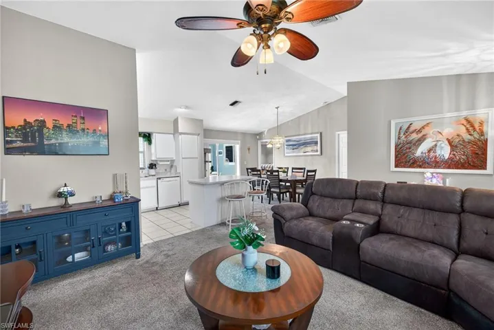 Living area with light colored carpet, ceiling fan, and light tile patterned floors