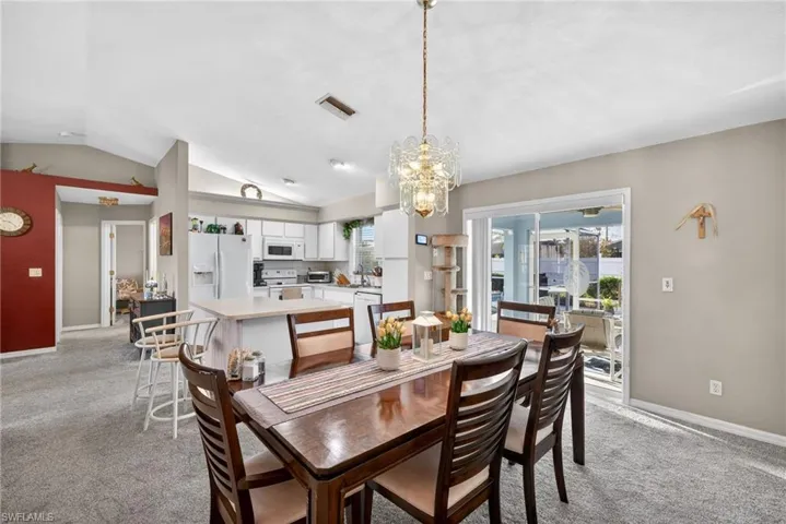 Dining area featuring light carpet, suspended lighting, and lofted ceiling