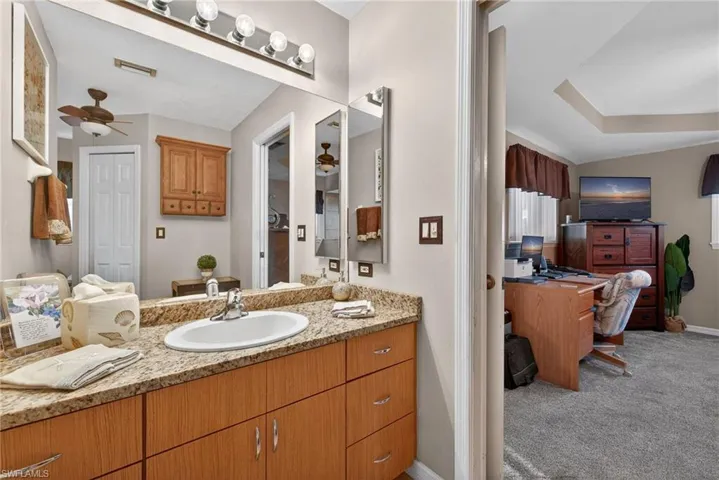 Bathroom with a ceiling fan, vanity, and light carpet
