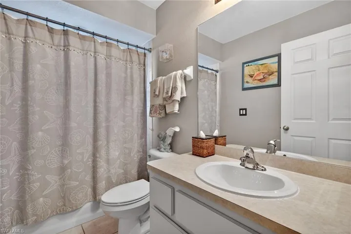 Bathroom with vanity, shower / bath combo with shower curtain, and light tile patterned flooring