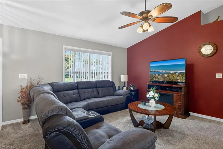 Living area featuring lofted ceiling, a ceiling fan, and carpet