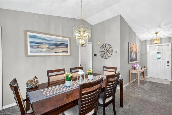 Dining area with carpet, vaulted ceiling, and a chandelier