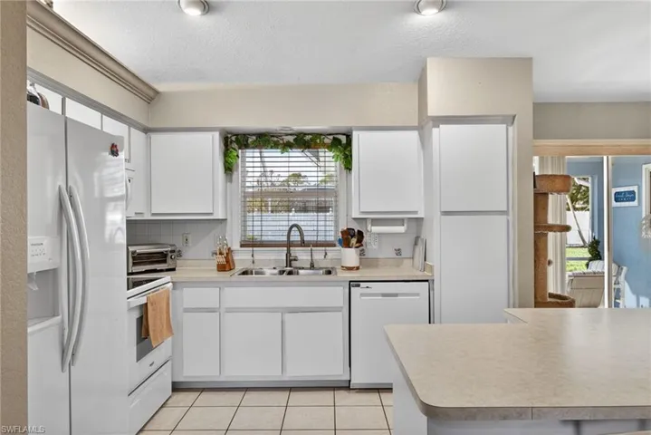 Kitchen with white appliances, white cabinetry, light countertops, a textured ceiling, and light tile patterned floors