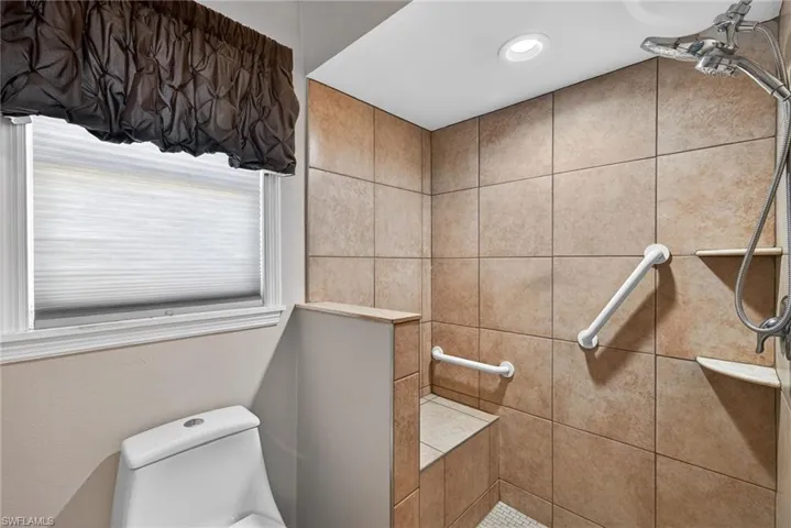 Bathroom featuring tiled shower and toilet
