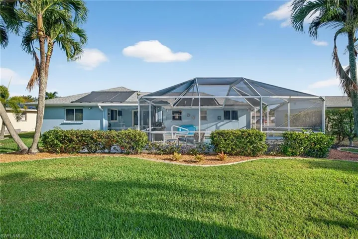 Rear view of property with a sunroom, glass enclosure, stucco siding, and a lawn