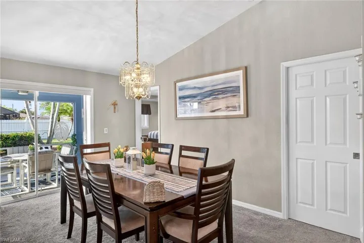 Carpeted dining area featuring hanging lights and lofted ceiling