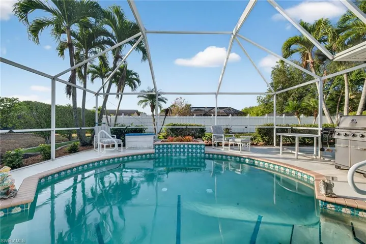 View of pool featuring a sunroom, glass enclosure, a grill, and patio surround
