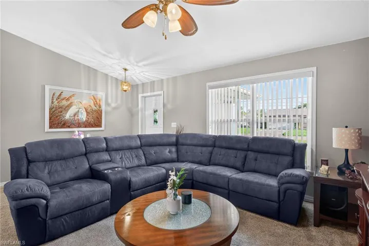 Carpeted living room with a ceiling fan
