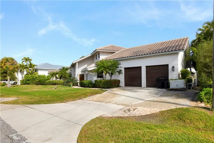 Mediterranean / spanish-style house featuring driveway, stucco siding, a front yard, and a tile roof