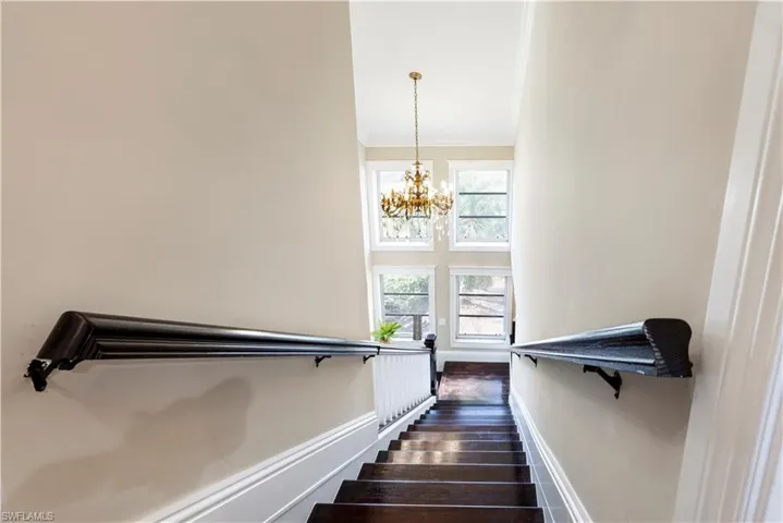 Stairway featuring crown molding, hardwood / wood-style flooring, and hanging lights