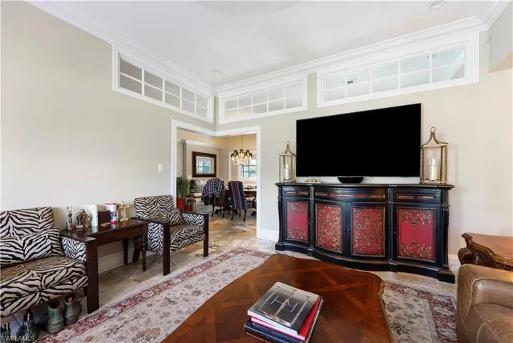 Living area with ornamental molding, hanging lights, and stone finish flooring