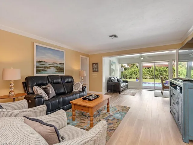 Living area featuring crown molding, ceiling fan, visible vents, and light wood finished floors