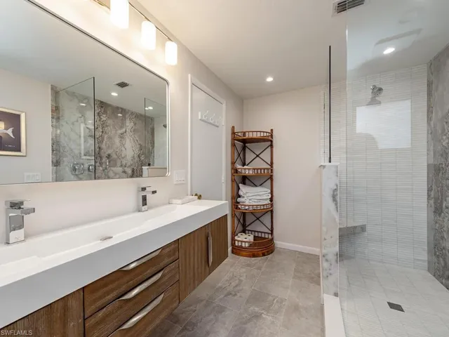 Bathroom featuring visible vents, double vanity, and walk in shower