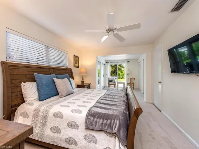 Carpeted bedroom with baseboards, visible vents, ceiling fan, and access to exterior