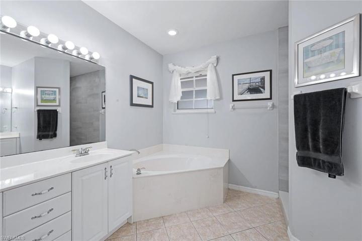 En suite bathroom with a soaking tub, separate newly tiled shower, and dual sinks,