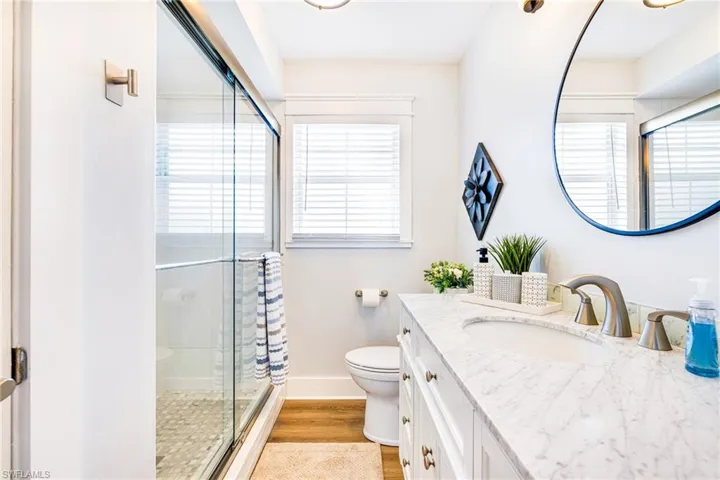 Bathroom featuring a spacious vanity with an undermount sink, a stone-finish countertop, and white cabinetry