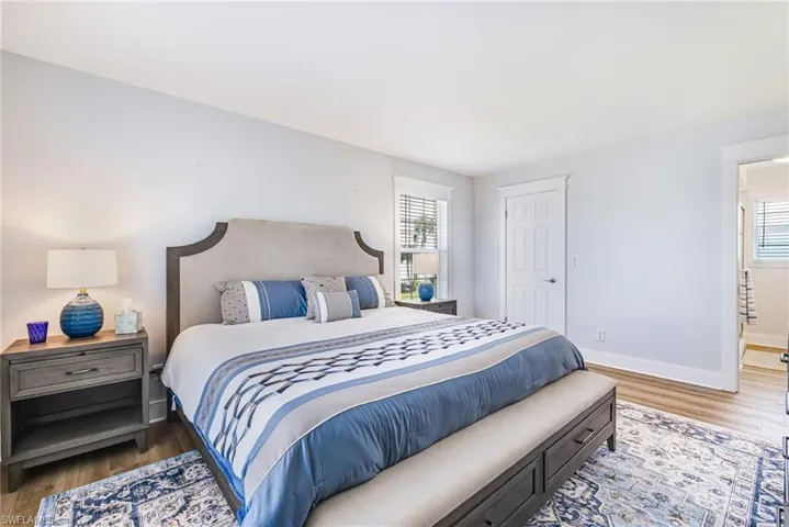 Spacious room featuring wood-finish flooring, a bright window with horizontal blinds, and a paneled door